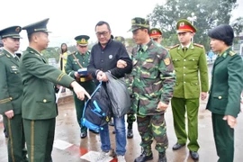 Công an Quảng Ninh trao trả đối tượng bị truy nã Quách Lâm (người đeo kính, mặc áo khoác đen) cho công an Trung Quốc. (Ảnh: Văn Đức/Vietnam+)