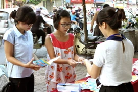 Cấp phát tờ rơi tuyên truyền chăm sóc sức khỏe sinh sản vị thành niên trên các tuyến phố. (Ảnh: Dương Ngọc/TTXVN)