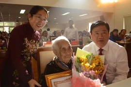 Bí thư Thành ủy Thành phố Hồ Chí Minh Đinh La Thăng trao bằng chứng nhận Bà mẹ Việt Nam Anh hùng cho mẹ Nguyễn Thị Trong. (Ảnh: Nguyễn Cúc/TTXVN)