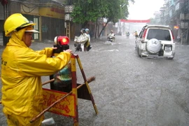 Cắm biển cảnh báo điểm nguy hiểm trên tuyến đường bị ngập lụt. (Ảnh: Nhật Anh/TTXVN)