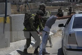 Binh sỹ Israel khám xét người dân Palestine tại một điểm kiểm soát ở trại tị nạn Fawwar ngày 16/8. (Nguồn: THX/TTXVN)