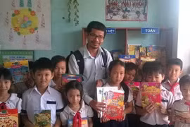Ông Nguyễn Quang Thạch và các em nhỏ bên những cuốn sách từ chương trình "Sách hóa nông thôn." (Nguồn: Vietnam+)