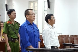 Bị cáo Nguyễn Văn Tuẫn (áo xanh dương) và bị cáo Bùi Mạnh Hà (áo trắng) đứng trước vành móng ngựa. (Ảnh: Kim Anh/TTXVN)
