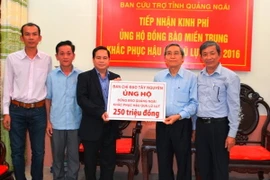 Phó trưởng ban Thường trực Ban Chỉ đạo Tây Nguyên Điểu K'RÉ trao tiền hỗ trợ cho đại diện Ủy ban Mặt trận Tổ quốc Việt Nam tỉnh Quảng Ngãi. (Ảnh: Phước Ngọc/TTXVN)