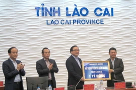 Bí thư Thành ủy Hà Nội Hoàng Trung Hải tặng quà và kinh phí hỗ trợ Quỹ xóa đói giảm nghèo tỉnh Lào Cai. (Ảnh: Hương Thu/TTXVN)