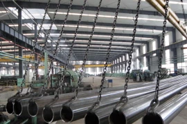 Công nhân kiểm tra ống thép inox chất lượng cao tại nhà máy ở huyện Ganyu, tỉnh Giang Tô, miền đông Trung Quốc. (Nguồn: THX/TTXVN)