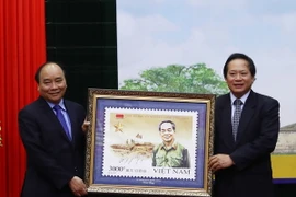 Bộ trưởng Bộ Thông tin và Truyền thông Trương Minh Tuấn thực hiện nghi thức trao tặng bộ tem cho Thủ tướng Nguyễn Xuân Phúc. (Ảnh: Thống Nhất/TTXVN)