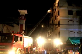 Cảnh sát Phòng cháy chữa cháy phun nước vào tầng 5 Công ty Kwong Lung-Meko để dập lửa. (Ảnh: Thanh Liêm/TTXVN)