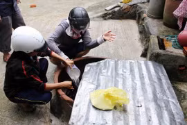Nhân viên y tế khử trùng giếng nước bị ngập lũ cho người dân huyện Đồng Xuân (Phú Yên). (Ảnh: Trần Lê Lâm/TTXVN)