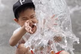 Một bé trai Hàn Quốc nghịch nước để tránh nóng. (Nguồn: BBC)
