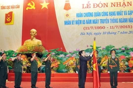 Chủ tịch nước Trương Tấn Sang gắn Huân chương Quân công hạng Nhất lên lá cờ truyền thống của Tổng cục Hậu cần. (Ảnh: Trọng Đức/TTXVN) 