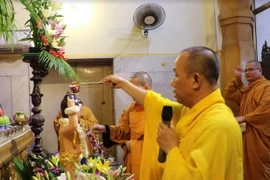 Thượng tọa Thích Hạnh Chánh cử hành nghi lễ tắm Phật. (Ảnh: Huy Bình/Vietnam+)