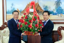 Đại sứ Nguyễn Bá Hùng đang nhờ Bộ trưởng Saleumsay Kommasith chuyển lẵng hoa của Thủ tướng Nguyễn Xuân Phúc tới Thủ tướng Lào Thongloun Sisoulith. (Ảnh: Phạm Kiên/Vietnam+)