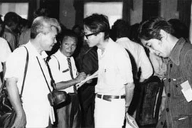 Tổng biên tập VNTTX Ðào Tùng (người đeo máy ảnh) gặp gỡ các phóng viên báo chí sau ngày giải phóng. (Nguồn: TTXVN)