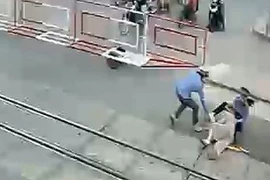 Cụ bà vấp ngã và được nhân viên gác chắn dũng cảm kéo ra khỏi đường ray đúng lúc đoàn tàu lao tới. (Ảnh: Trích từ camera an ninh)