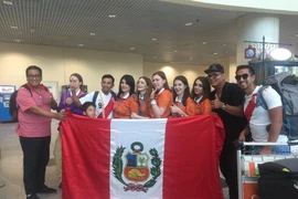 Các tình nguyện viên (áo cam) chụp ảnh lưu niệm cùng cổ động viên nước ngoài. (Ảnh: Trần Giáp/Vietnam+)