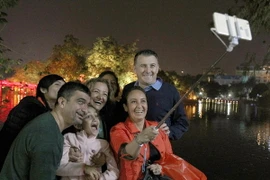 Du khách nước ngoài hào hứng chụp ảnh kỷ niệm thời khắc giao thừa bên hồ Hoàn Kiếm Hà Nội. (Ảnh: Quốc Khánh/TTXVN)