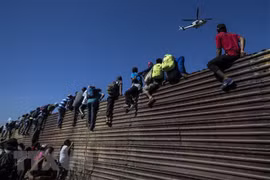 Người di cư vượt qua hàng rào biên giới giữa Mỹ và Mexico, gần cửa khẩu El Chaparral ở Tijuana, bang Baja California, Mexico ngày 25/11/2018. (Ảnh: AFP/TTXVN)