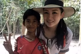 Cậu bé Campuchia chụp ảnh cùng nữ du khách. (Nguồn: nextshark.com)