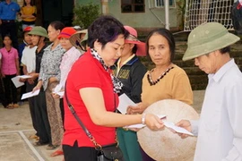 Phó Tổng biên tập báo VietnamPlus, Đoàn Ngọc Thu (áo đỏ) trao quà cho người dân. (Ảnh: Thành Long/Vietnam+) 