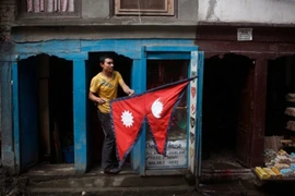 Một người dân cầm lá quốc kỳ Nepal bên ngoài quầy hàng của mình ở Kathmandu. (Nguồn: AP/CNN)