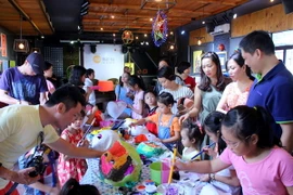 Các em nhỏ say sưa vẽ mặt nạ. (Ảnh: CTV Hải An/Vietnam+)