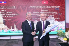 Phó Chủ tịch UBND Thành phố, Chủ tịch Hội hữu nghị Việt Nam-Lào Thành phố Hồ Chí Minh Ngô Minh Châu (trái) tặng hoa chúc mừng Tổng lãnh sự Lào tại Thành phố Hồ Chí Minh Phonesy Bounmixay (phải). (Ảnh: Xuân Khu/TTXVN)