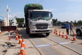 Lực lượng chức năng tiến hành kiểm tra trọng tải xe. (Ảnh: Thế Lập/TTXVN)