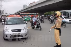 Cảnh sát giao thông xử phạt xe taxi vi phạm Luật giao thông. (Ảnh: Việt Hùng/Vietnam+)