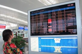 Hành khách xem hệ thống bảng điện tử chuyến bay tại sân bay Nội Bài. (Ảnh: Việt Hùng/Vietnam+)