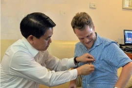 Chủ tịch Nguyễn Đức Chung đã tặng và tự tay gắn lên ngực áo anh James Joseph Kendall logo của thành phố Hà Nội. (Ảnh: /Vietnam+)