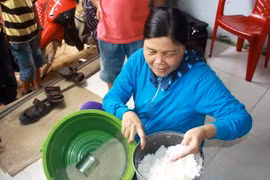 Bà Trương Thị Bé Đoan, khu dân cư số 7, cầm số gạo nghi trộn nhựa. (Ảnh: Vĩnh Trọng/TTXVN)