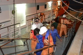 Một thuyền viên sức khỏe còn yếu được lực lượng cứu nạn tàu SAR 412 đưa lên bờ. (Ảnh: Đinh Văn Nhiều/TTXVN)