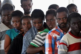 Người di cư xếp hàng nhận đồ ăn trên tàu Hải quân Đức sau khi được cứu vớt trên biển Địa Trung Hải. (Nguồn: AFP/TTXVN)