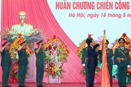 Chủ tịch nước Võ Văn Thưởng gắn Huân chương Chiến công hạng Nhất lên lá cờ truyền thống của Tổng Cục II, Bộ Quốc phòng. (Ảnh: Thống Nhất/TTXVN)