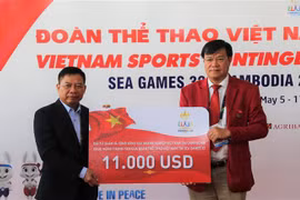 Đại sứ Nguyễn Huy Tăng (trái) tặng quà, chúc mừng Đoàn thể thao Việt Nam. (Ảnh: Hoàng Minh/TTXVN)