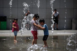 Trẻ em giải nhiệt tránh nóng tại một đài phun nước ở Hong Kong, Trung Quốc. (Ảnh: AFP/TTXVN)