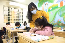 Cô giáo Nghiêm Thị Như Ý hướng dẫn học sinh lớp 2G - Trường tiểu học Phạm Tu (Thanh Trì) tập viết. (Ảnh: Hoàng Hiếu/TTXVN)