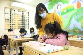 Cô giáo Nghiêm Thị Như Ý hướng dẫn học sinh lớp 2G - Trường tiểu học Phạm Tu (Thanh Trì) tập viết. (Ảnh: Hoàng Hiếu/TTXVN)
