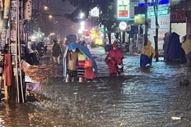 Người dân vất vả di chuyển giữa làn nước trên đường Đặng Thị Rành (thành phố Thủ Đức). Ảnh: (Hồng Giang/TTXVN)