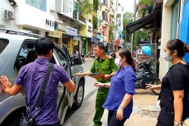 Cơ quan chức năng dẫn giải những người liên quan đi sau khi thực hiện việc khám xét Công ty PIT Travel. (Ảnh: TTXVN phát)