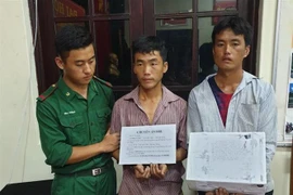 Hai đối tượng cùng tang vật tại cơ quan điều tra. (Ảnh: Xuân Tư/TTXVN)
