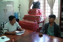Đối tượng Lâm Bài Cào và tang vật thuốc lá điếu nhập lậu tại Đội cảnh sát điều tra Công an huyện Trảng Bàng. (Ảnh: Lê Đức Hoảnh/TTXVN)