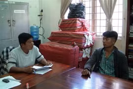 Đối tượng Lâm Bài Cào và tang vật thuốc lá điếu nhập lậu tại Đội cảnh sát điều tra Công an huyện Trảng Bàng. (Ảnh: Lê Đức Hoảnh/TTXVN)