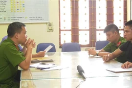 Đối tượng Nguyễn Văn Tường (áo đen, bên phải) tại cơ quan Cảnh sát điều tra. (Ảnh: TTXVN phát)