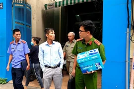 Cơ quan chức năng dẫn giải những người liên quan đi sau khi thực hiện việc khám xét Công ty PIT Travel. (Ảnh: TTXVN phát)