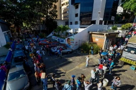 Người dân Venezuela xếp hàng chờ đổi tiền bên ngoài ngân hàng trung ương ở Caracas. (Nguồn: AFP/TTXVN)