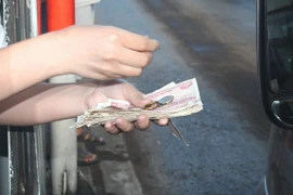 Tài xế dùng tiền mệnh giá nhỏ để mua vé qua trạm. (Ảnh: Công Phong/TTXVN)