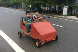 Em Lê Thiên Ân điều khiển chiếc xe ô tô có khung bằng gỗ, chạy bằng nguồn điện ắc quy vừa mới chế tạo. (Ảnh: Hồ Cầu/TTXVN)