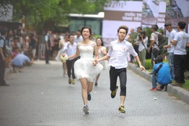 Các cặp đôi vẫn diện những bộ lễ phục đám cưới rất đẹp nhưng thay vì đi giày da và guốc, họ sắm cho mình những đôi giày chạy bộ. (Ảnh: Minh Sơn/Vietnam+)